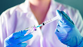 female Doctor hand holding syringe and covid-19 vaccine in blue gloves with white coat. Disease injection concept.