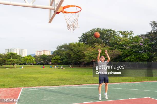 hogere basketbalspeler die bal naar hoepel werpt - jump shot stockfoto's en -beelden