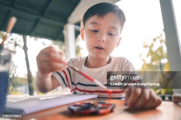 boy painting with watercolor brush - concentration camp photos photos et images de collection