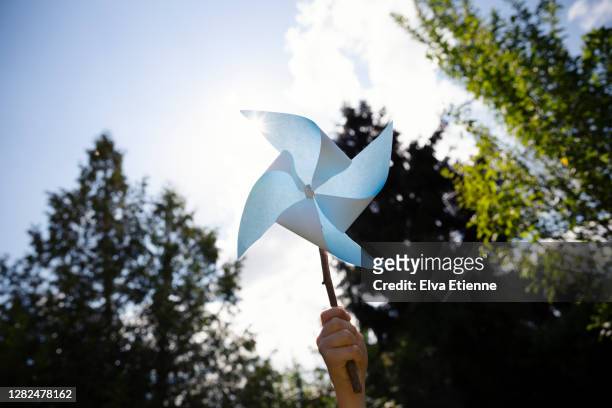 blue paper windmill held high in the air in a child's hand - paper windmill stock pictures, royalty-free photos & images