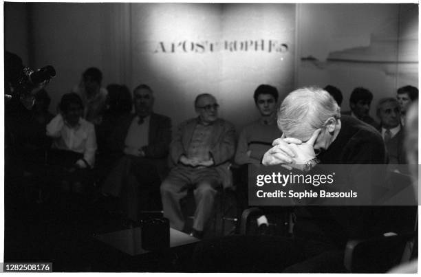 Czech writer Milan Kundera holds his head in clasped hands during an appearance on the French literary television show Apostrophes.