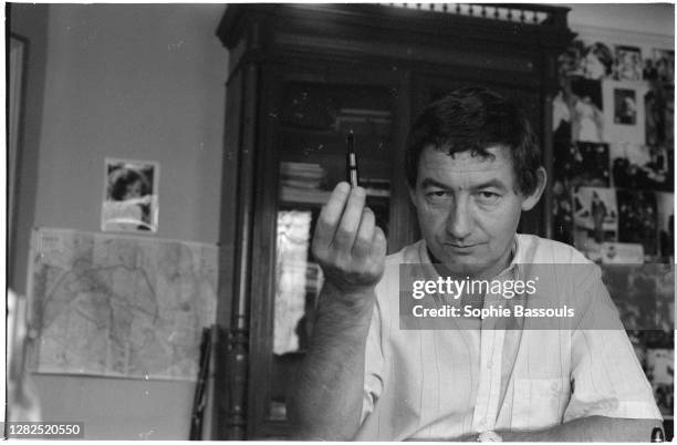 Pierre Desproges holds up a pen. Desproges is a popular French journalist and humorist.