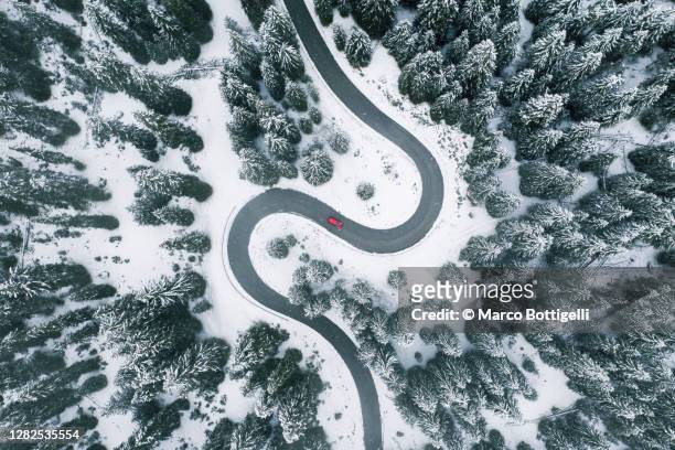 aerial view of winding road in winter forest - winter stock-fotos und bilder