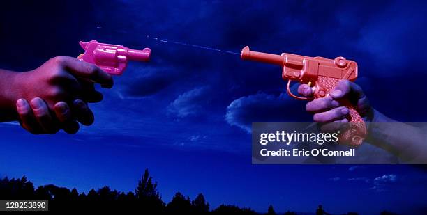 two hands with waterguns pointing at each other - waterpistool stockfoto's en -beelden