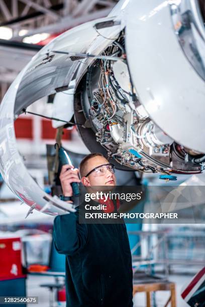 junger männlicher ingenieur, der den flugzeugjet überprüft - flugzeugmechaniker stock-fotos und bilder