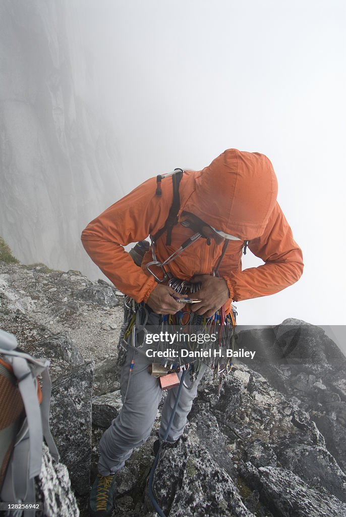 Mountain climber racking his gear in foggy weather