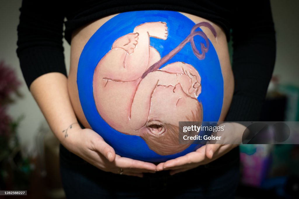 Baby painting on pregnant belly.