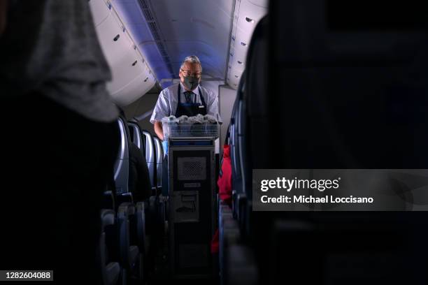 Masked flight attendant passes out refreshments on a flight from San Francisco, California to Newark, New Jersey on October 27, 2020. Although virus...