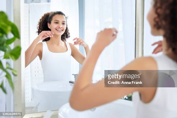 mooi jong meisje met krullend haar dat in de spiegel in badkamers kijkt - girls taking a showering stockfoto's en -beelden