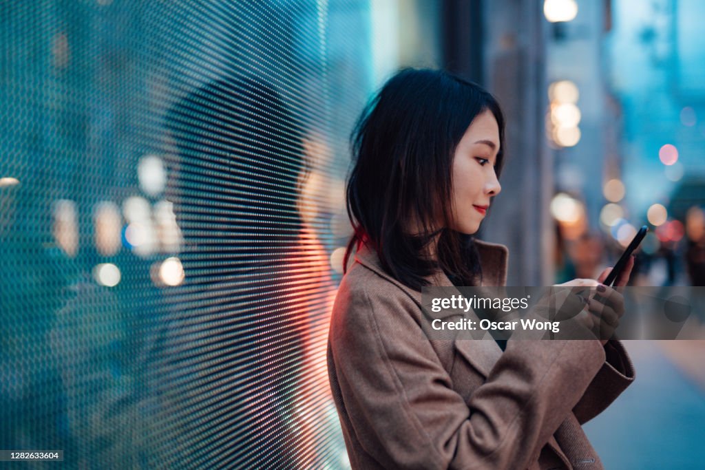 Connect the future - young woman using mobile phone on street