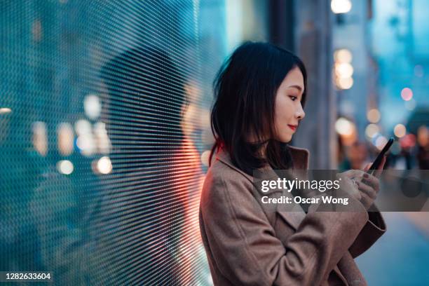 connect the future - young woman using mobile phone on street - china smartphone stock pictures, royalty-free photos & images