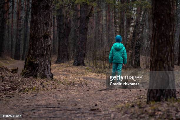 lonely kid leaving alone along a forest path in the evening - faze rug stockfoto's en -beelden