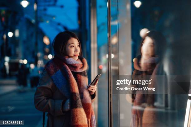 young woman window shopping in the city at night - fashion hong kong stock-fotos und bilder