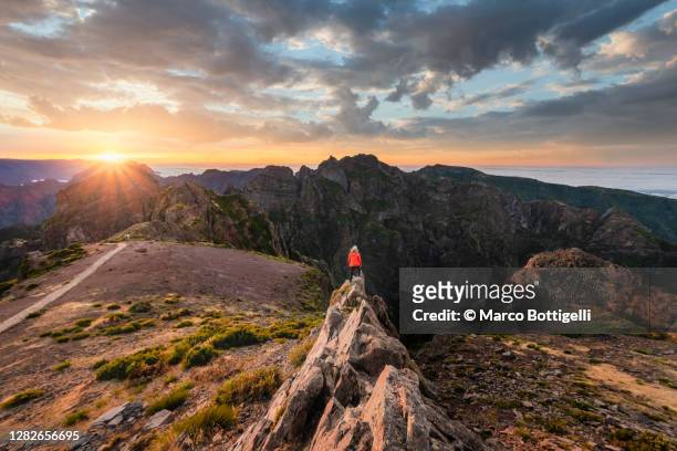 woman standing on top of a rock admiring sunset at pico do arieiro, madeira, portugal - pico do arieiro fotografías e imágenes de stock