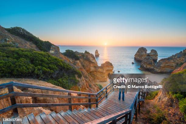 tourist photographing the sunset at praia do camilo, lagos, portugal - lagos stock pictures, royalty-free photos & images