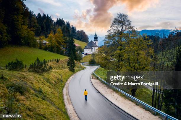 person walking on the road towards maria gern church, bavaria, germany - berchtesgaden alps stock pictures, royalty-free photos & images