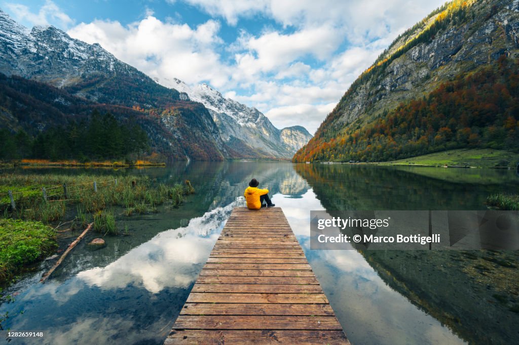 One man sitting on a boat pier admiring the Konigssee lake, Bavaria, Germany