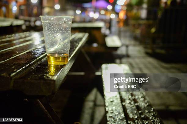 an almost empty beer cup at a patio table - empty beer glass stock pictures, royalty-free photos & images