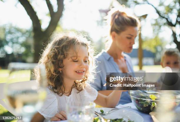 small girl with mother on outdoor summer garden party, eating. - eating chicken stock-fotos und bilder