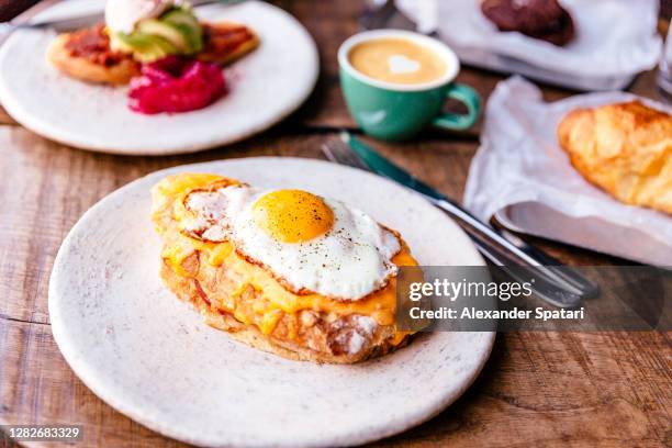 close-up of croque madame with fried sunny side up egg on the table - setzei stock-fotos und bilder