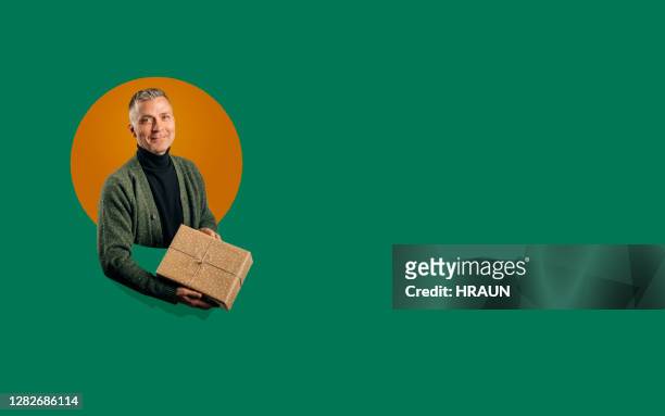 man smiling to the camera holding a gift in his hand - heritage round one stock pictures, royalty-free photos & images