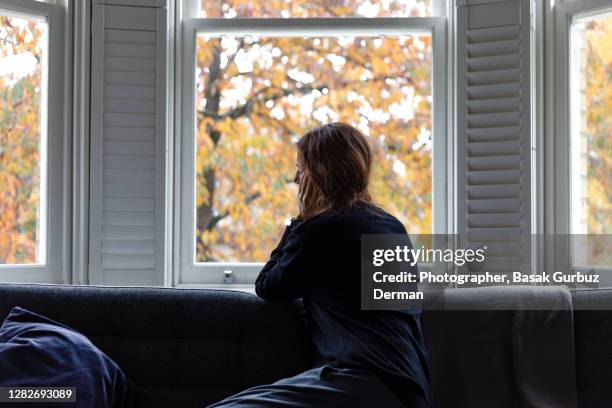 a woman looking through the window... social distancing. - depressie verdriet stockfoto's en -beelden
