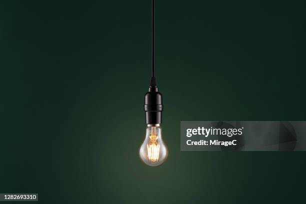 retro style light bulb on dark green - luz colgante fotografías e imágenes de stock