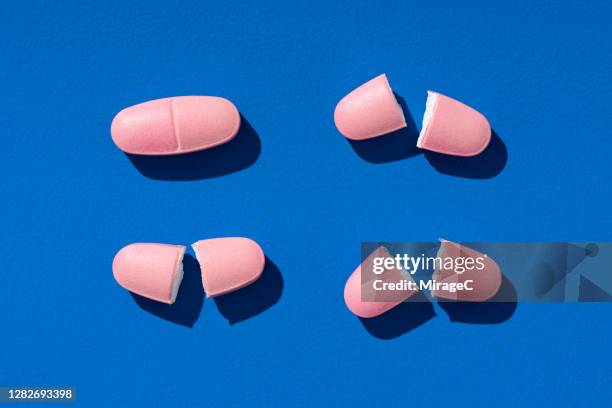 halved and whole pills on blue - dividir fotografías e imágenes de stock
