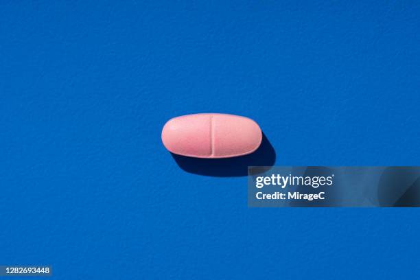 pink pill on blue - kapsel stock-fotos und bilder