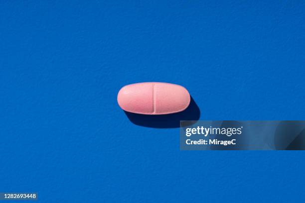 pink pill on blue - enkel object stockfoto's en -beelden