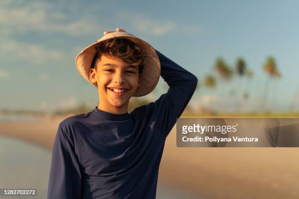porträt eines jungen mit hut am strand - boy in swimwear stock-fotos und bilder