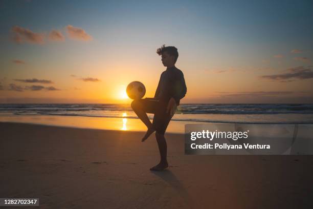 junge balanciert ball auf knie bei sonnenaufgang - brazilian playing football stock-fotos und bilder