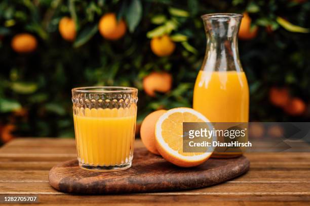 köstlicher frisch gepresster orangensaft aus bio-orangen aus dem eigenen baum - orange juice stock-fotos und bilder