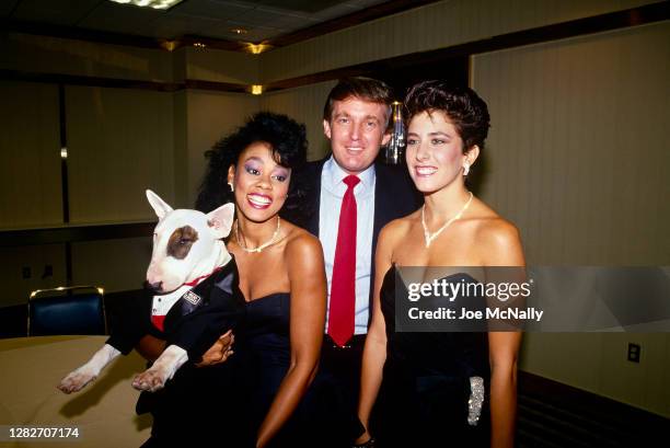 Donald Trump with his arms around two unidentified women, one of whom is holding Spuds MacKenzie, the bull terrier who was the Bud Light mascot.