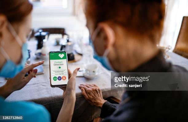district nurse explaining a covid-19 tracking app to a patient - spy hunter stock pictures, royalty-free photos & images