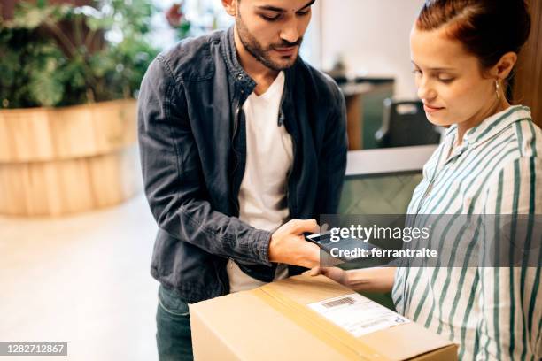 courier scanning package at office reception - picking up mail stock pictures, royalty-free photos & images