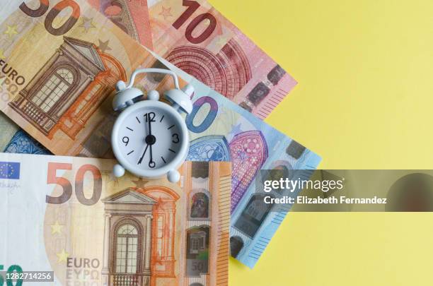 vintage alarm clock over european union euro notes on yellow background - orange alarm clock stock pictures, royalty-free photos & images