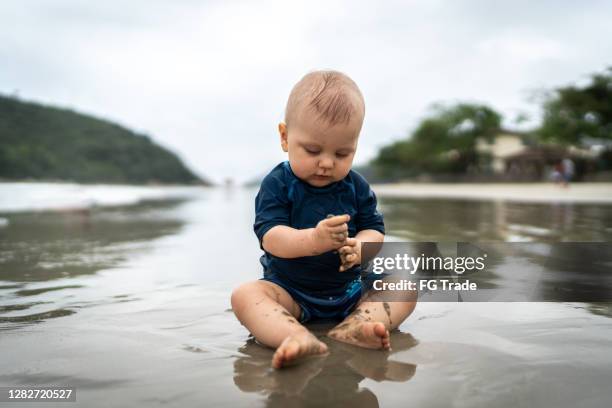 cute baby playing in the sand at the beach - boy exploring on beach stock pictures, royalty-free photos & images