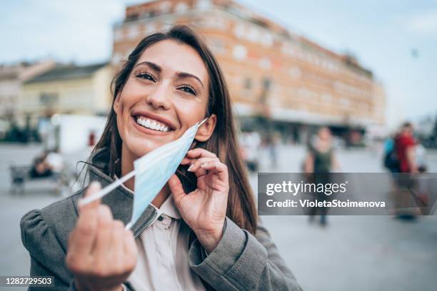 woman with protective face mask outdoors. - taking off imagens e fotografias de stock