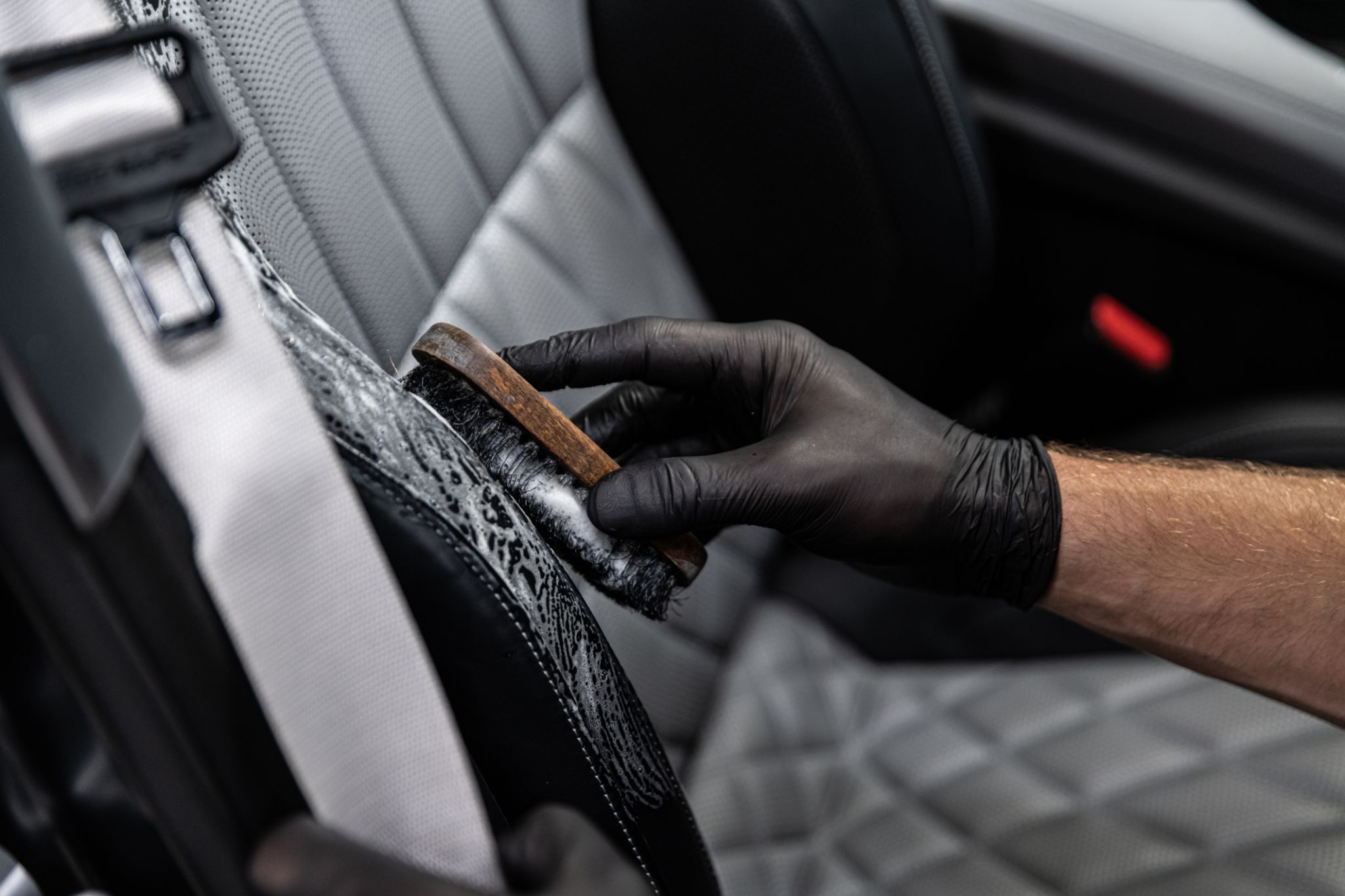 Car detailing studio worker cleaning car interior and car leather seats with a brush. Car detailing studio worker cleaning car interior and car leather seats with a brush.