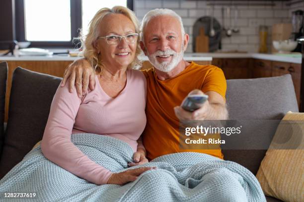 casal de idosos relaxando no sofá em casa assistindo tv - maratona de televisão - fotografias e filmes do acervo