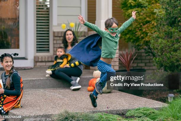 boy in superhero costume jumping for joy on halloween - halloween covid stock pictures, royalty-free photos & images