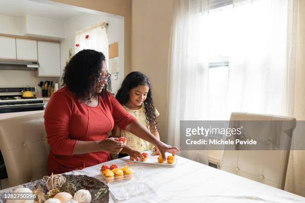 black aunt and niece arranging cupcakes at home - aunt niece stock pictures, royalty-free photos & images