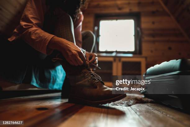 mujer joven sentada en la cama y atando cordón de zapatos en las botas - woman boots fotografías e imágenes de stock
