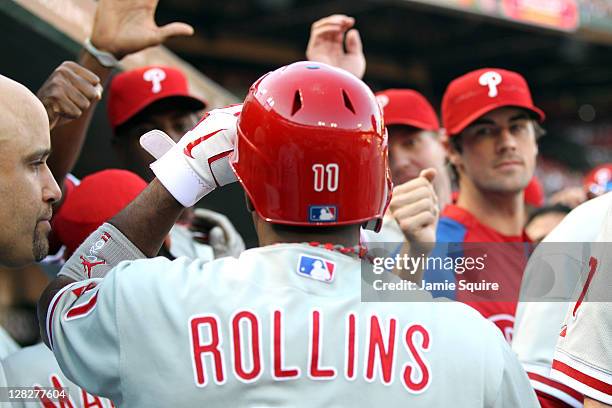 Jimmy Rollins of the Philadelphia Phillies is greeted by his teammates in the dugout after scoring on a Chase Utley triple in the first inning...