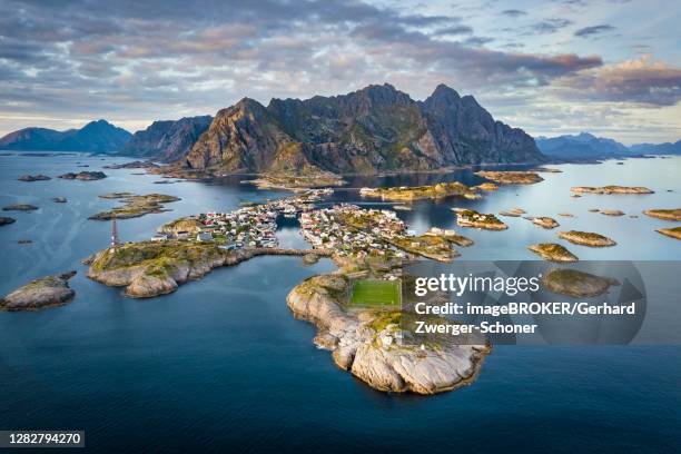 aerial view of the island world near the fishing village henningsvaer, in front peninsula with football field, in the back mountain range vagakallen with summits festvagtinden, budalsdinten and kvanndalstinden, vagan, lofoten, nordland, norway - henningsvaer stock pictures, royalty-free photos & images