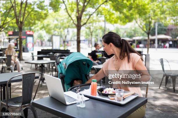 young woman having lunch outdoors in restaurant, while her baby sleeping in a stroller. - belgrade cafe stock pictures, royalty-free photos & images