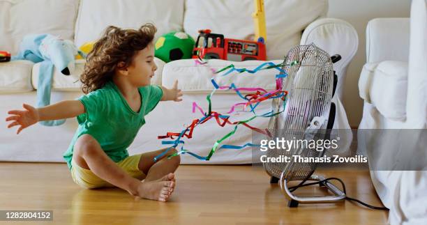 three year old boy standing in front of a fan and enjoy cool waves - electric fan stock pictures, royalty-free photos & images