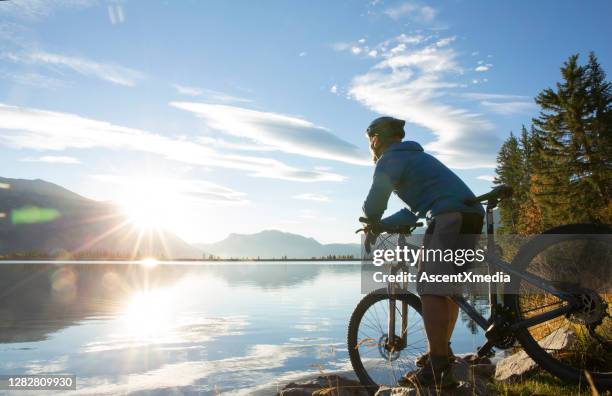 de fietser van de mountainbike ontspant door meershore bij zonsopgang - lakeshore stockfoto's en -beelden