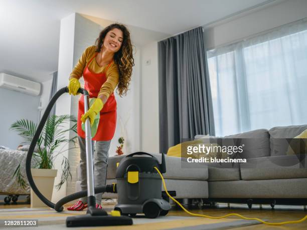 gelukkige vrouw die tapijt met stofzuiger schoonmaakt - vacuum cleaner woman stockfoto's en -beelden